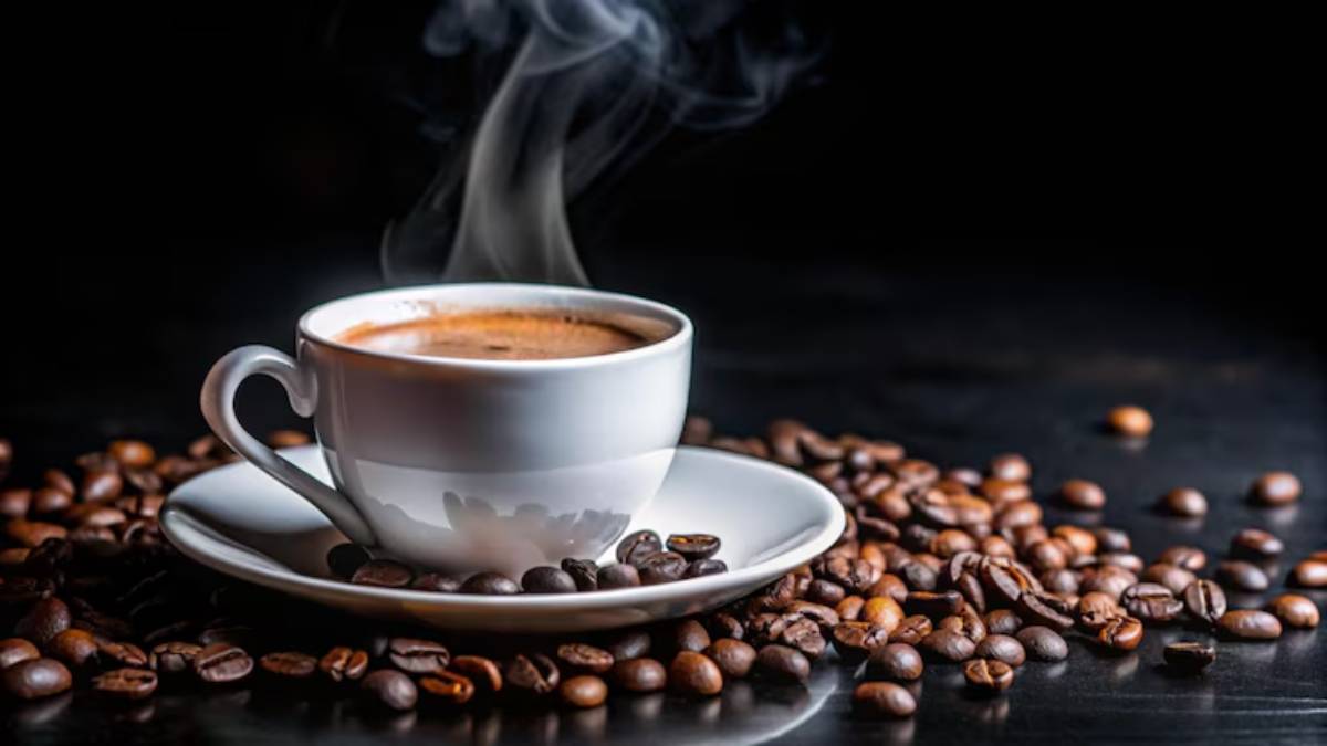 A steaming cup of coffee sits on a saucer, surrounded by scattered coffee beans against a dark background.